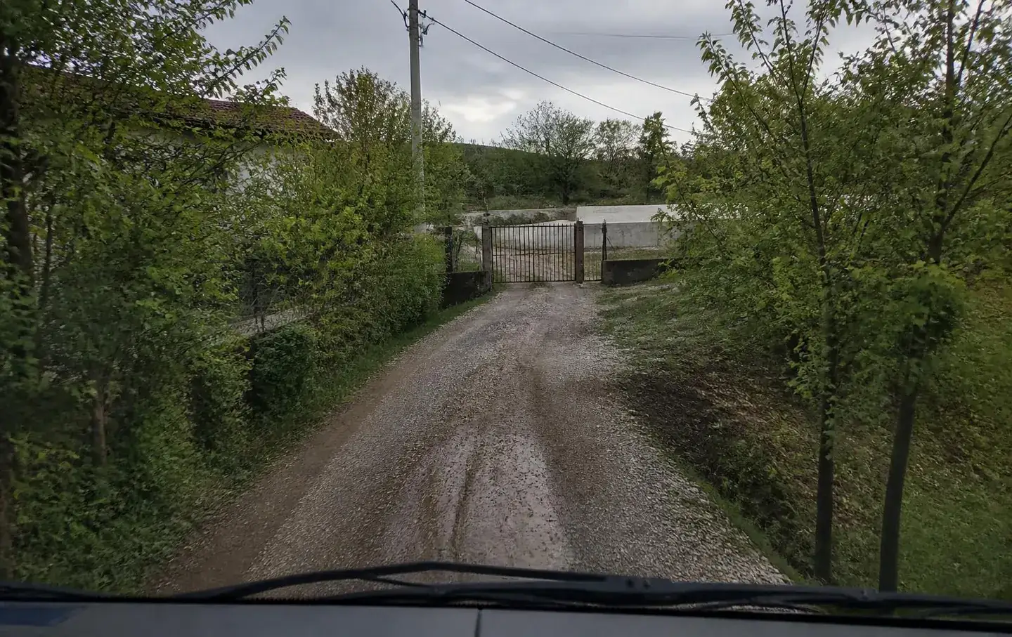 Вид с места водителя: узкий гравийный подъезд к воротам участка